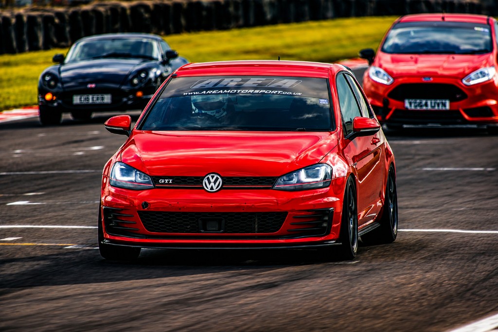 Red Volkswagen Golf GTI and other cars on a racetrack